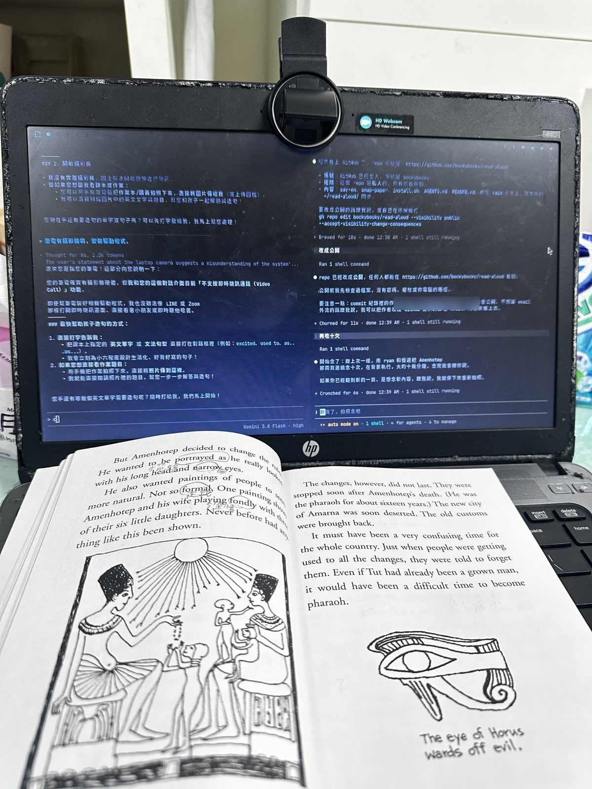那天晚上的實景:舊筆電螢幕上方夾著網路攝影機,右邊視窗的 AI 正在用慢速念課文,筆電前面攤著那本古埃及讀本